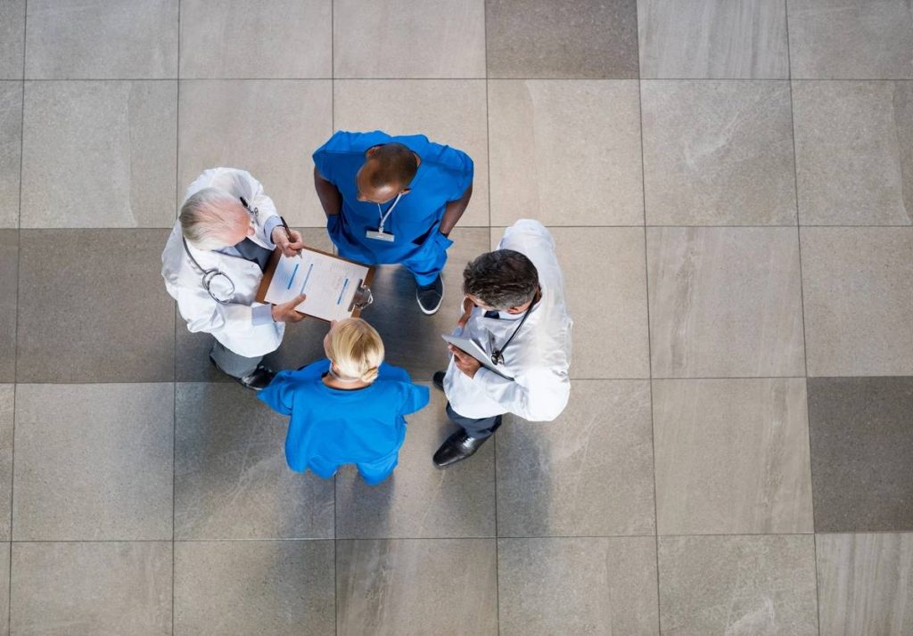 High angle view of senior doctors and young surgeons discussing over patient case. Top view of group of doctor in a conversation with copyspace. Doctors and nurses talking to each other about medical results. (High angle view of senior doctors and you